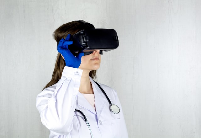 young female doctor graduate using VR AI augmented reality goggles to view the virtual clinic for telehealth