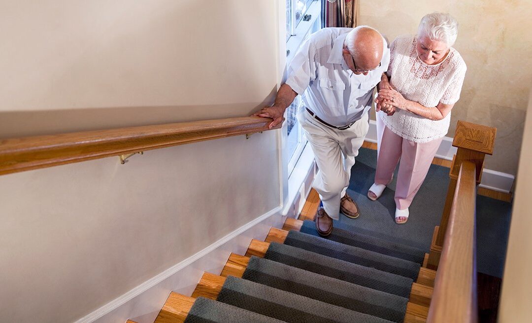 elderly man walking up the stairs with the help of his wife