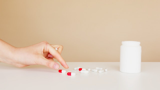 woman taking her red pill medications for her chronic disease management