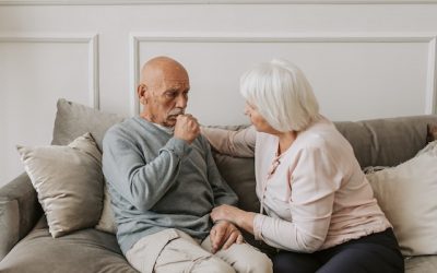 elderly man coughing while being nursed by his wife at home