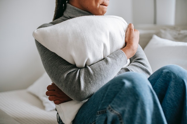 Middle aged black woman hugging a pillow for comfort from her anxiety and stress