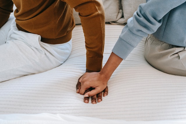 interracial couple holding hands intimately in bed