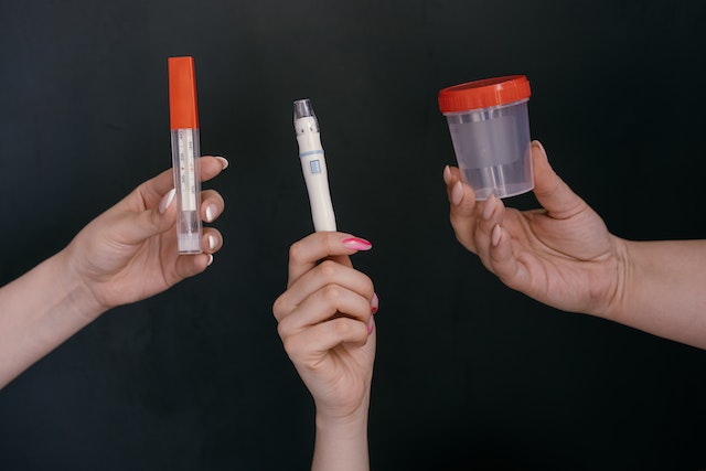Phot of a 3 people holding aset of urine testing kits